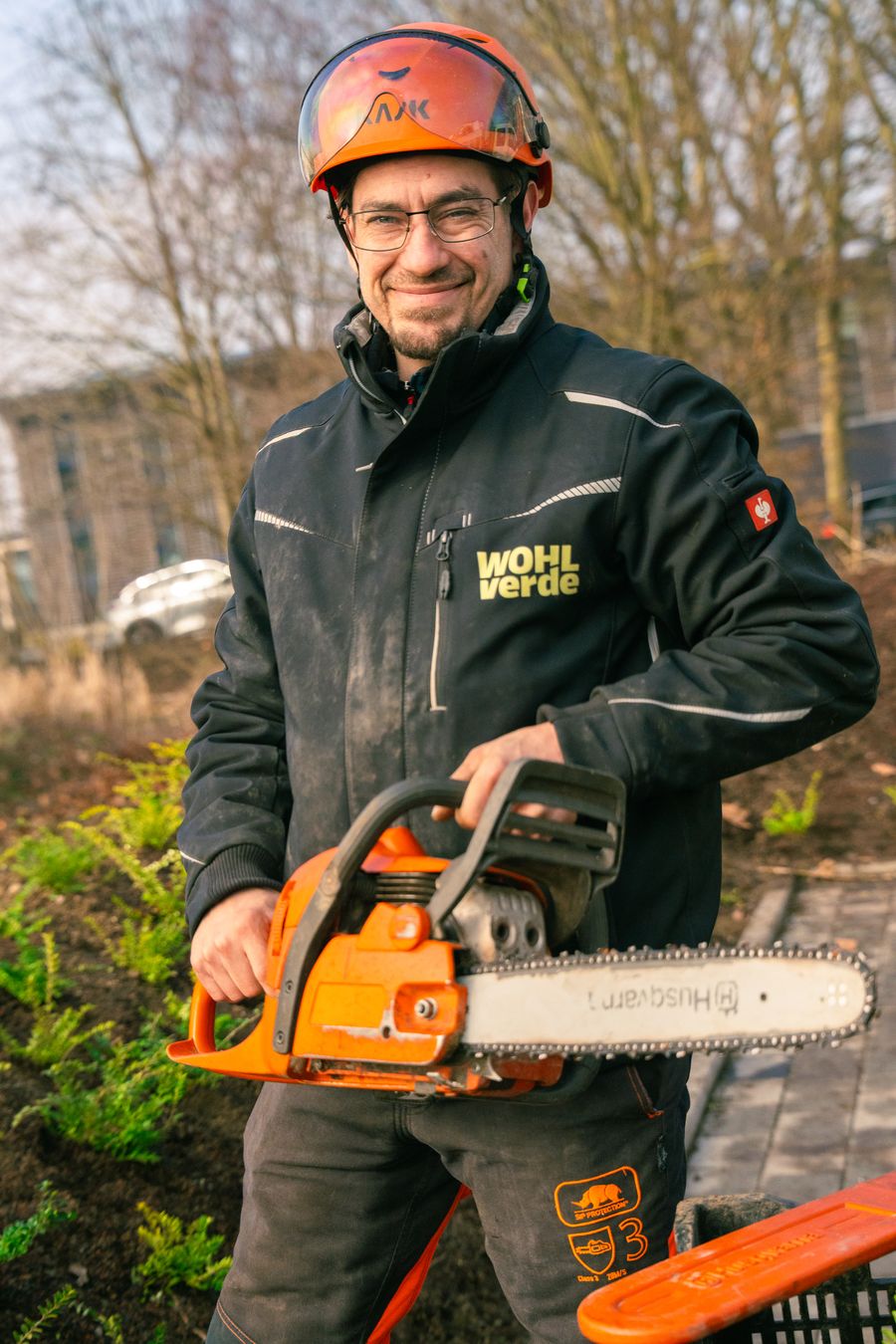 WOHLverde-Mitarbeiter mit Helm und Motorsäge