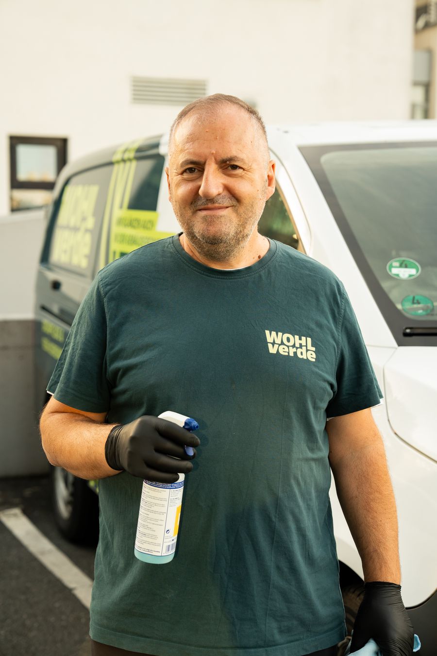 WOHLverde-Mitarbeiter mit Reinigungsmittel vor dem Firmenwagen