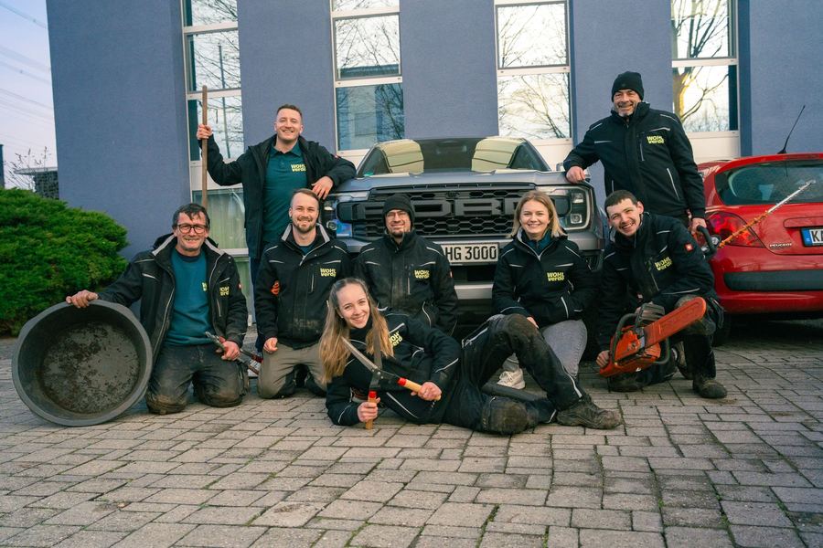 Das WOHLverde-Team in Winterkleidung mit Fahrzeug vor einem Bürogebäude